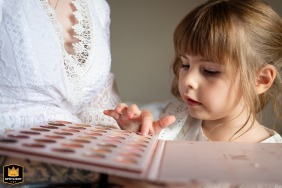 In Sarrebourg, France, a touching moment captured on the wedding day as the bride's daughter playfully experiments with makeup during a behind-the-scenes documentary shot at the venue.